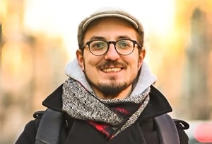 Piotr Salata-Kochanowski, a brunette man wearing glasses, a beard and a flat cap