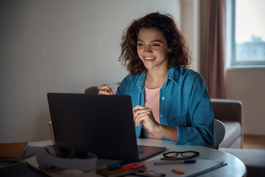 A student is smiling in front of her laptop.