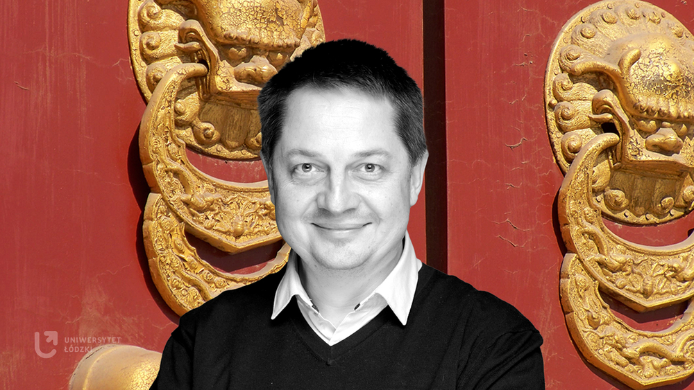 A black-and-white image of Professor Mierzejewski against the background of two large golden Asian bas-reliefs in the shape of large door knockers