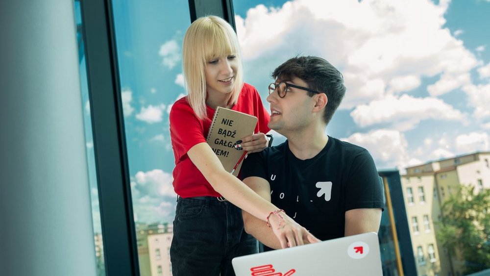 a girl and a boy sitting at a laptop