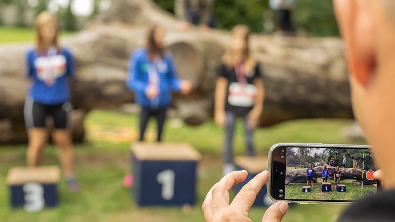 Osoba robi telefonem zdjęcie zawodnikom stojącym na podium 