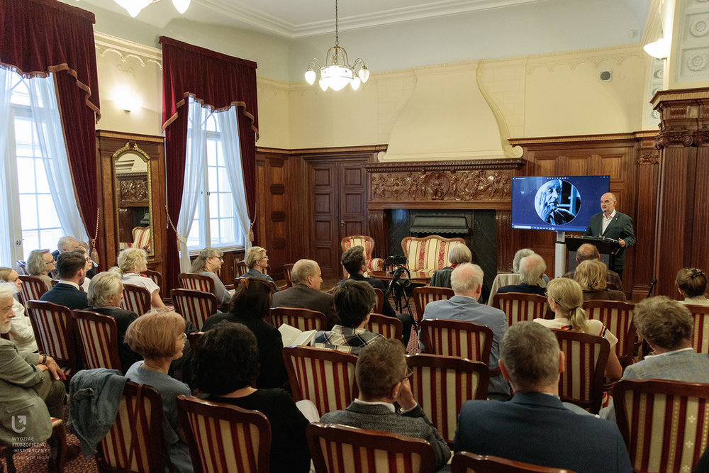Zdjęcie osób siedzących na krzesłach w zabytkowej sali Zdjęcie osób siedzących na krzesłach w zabytkowej sali