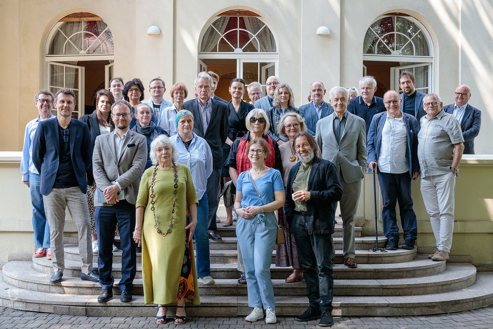 Fotografia ludzi stojących przed budynkiem na schodach 
