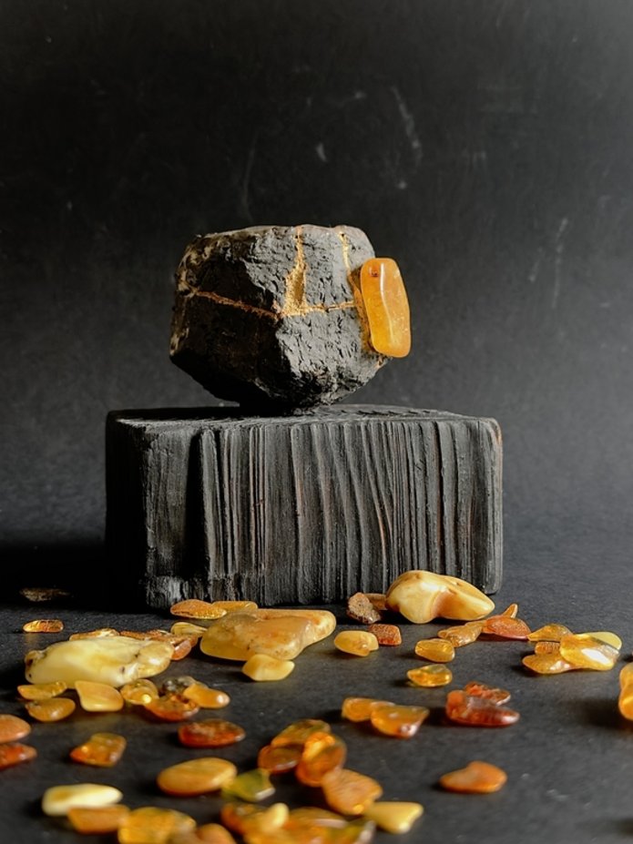 The photo shows a sculpture and amber on a black background.
